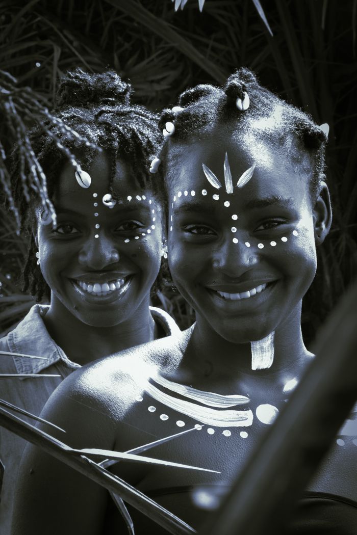 Two women with traditional face paint smiling, representing cultural beauty.