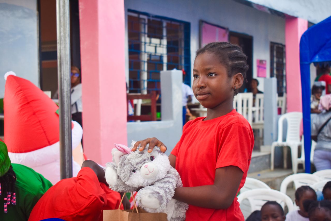 A girl in Monrovia, Liberia, holds a plush toy during a festive outdoor event.