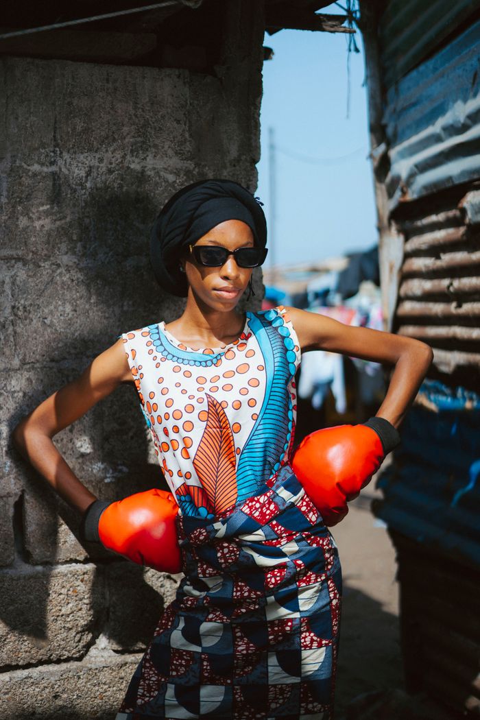 Stylish woman with red boxing gloves in Monrovia, showing vibrant fashion amidst urban backdrop.