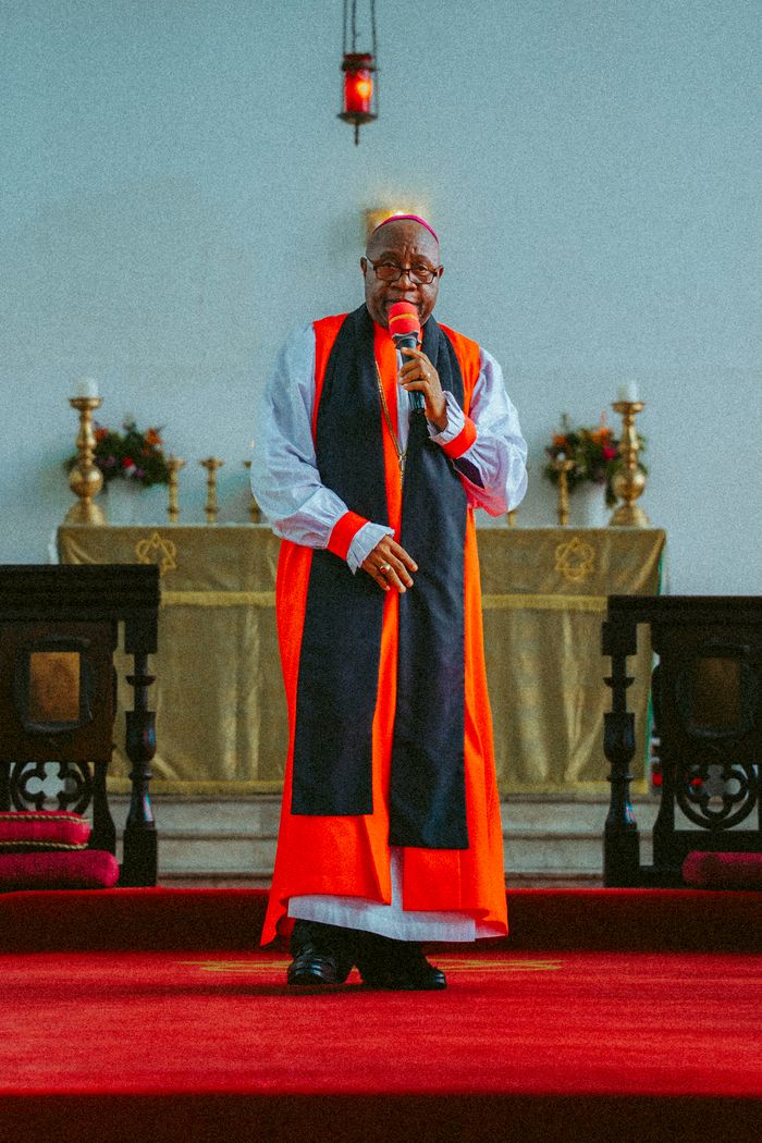 Bishop delivering a sermon in a Monrovia church, wearing traditional vestments.